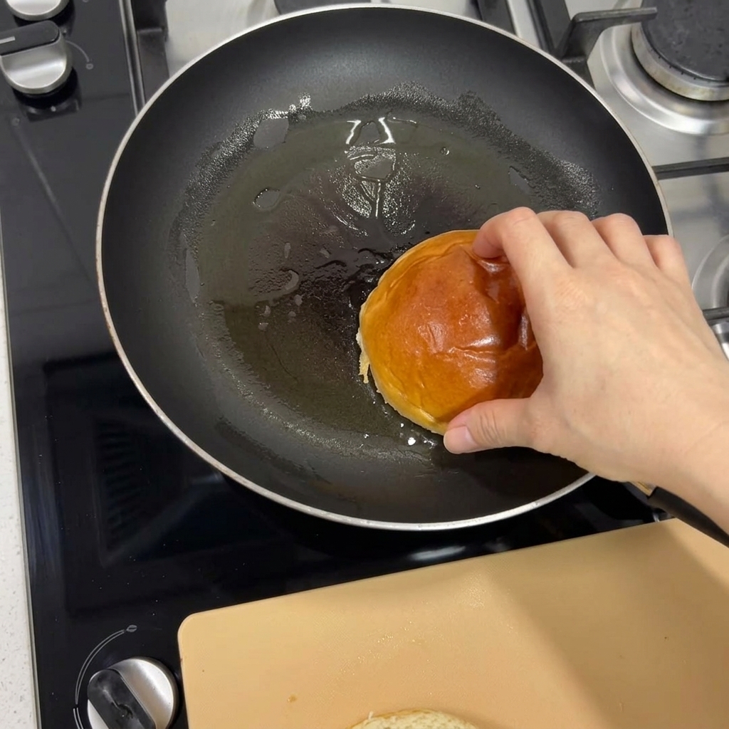 Une main plaçant un pain brioché dans une poêle chaude pour le faire griller jusquà ce quil soit doré.