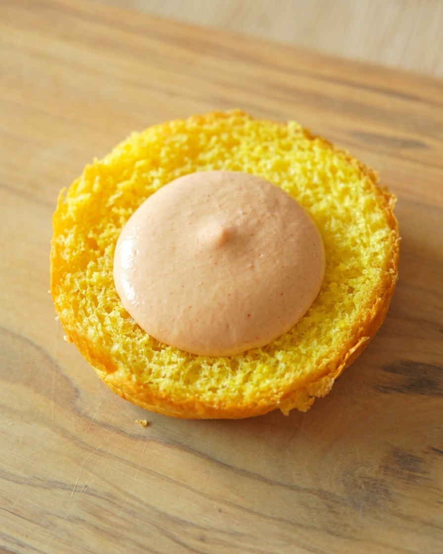 Base dun pain brioché toasté avec une généreuse dose de sauce burger orange étalée au centre.