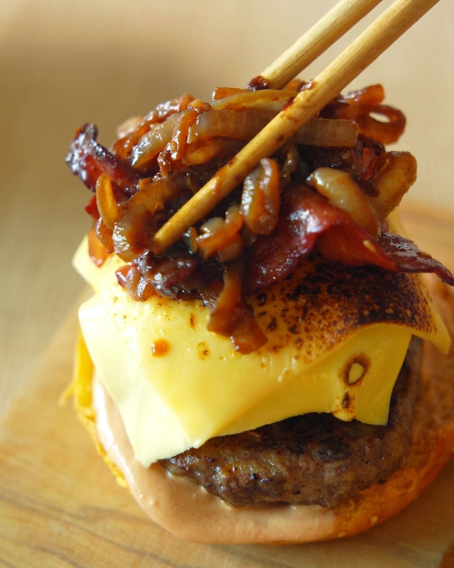 Bacon croustillant et oignons caramélisés délicatement déposés sur le steak au fromage avec des baguettes.