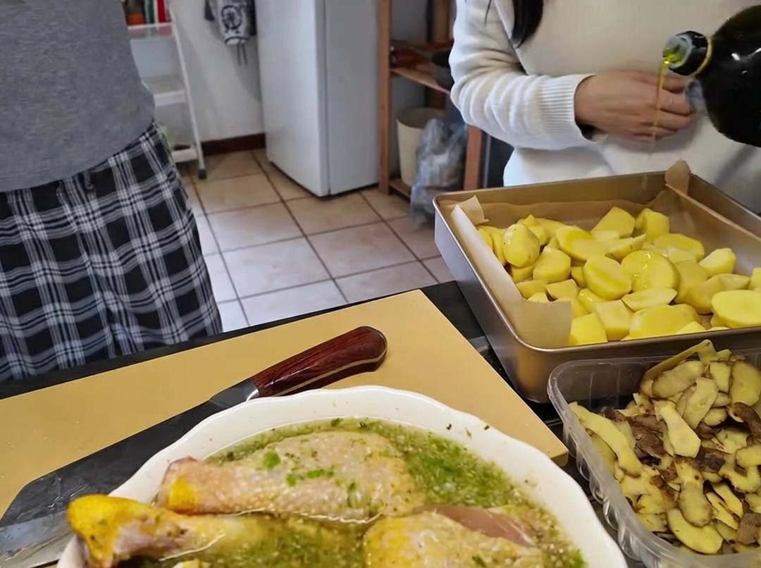 Versement dhuile dolive depuis une bouteille en verre sur une plaque de cuisson remplie de morceaux de pommes de terre.