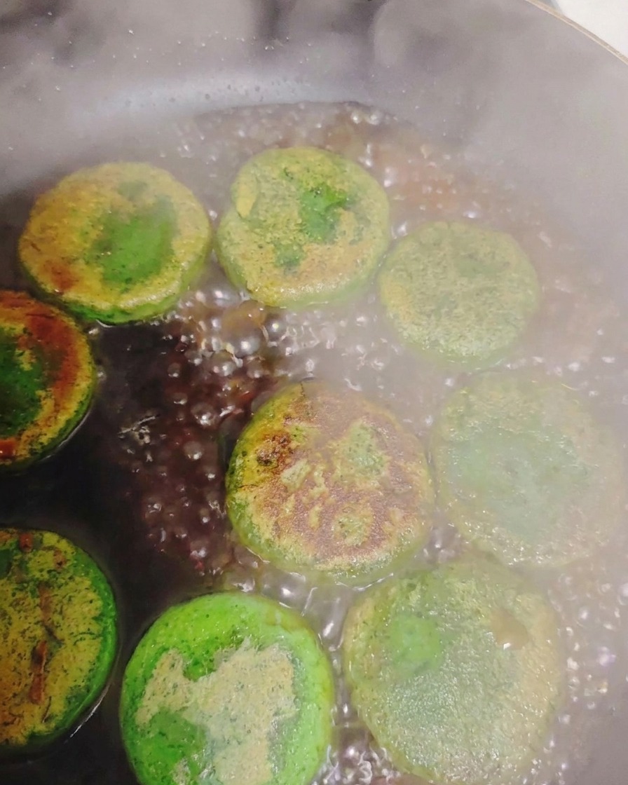 De leau qui bout et crée de la vapeur autour de galettes de légumes poêlées dans une poêle chaude.