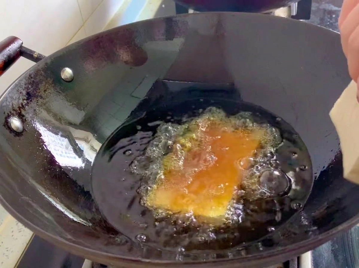 Blocs de tofu ferme en train de frire dans un wok rempli dhuile bouillante.