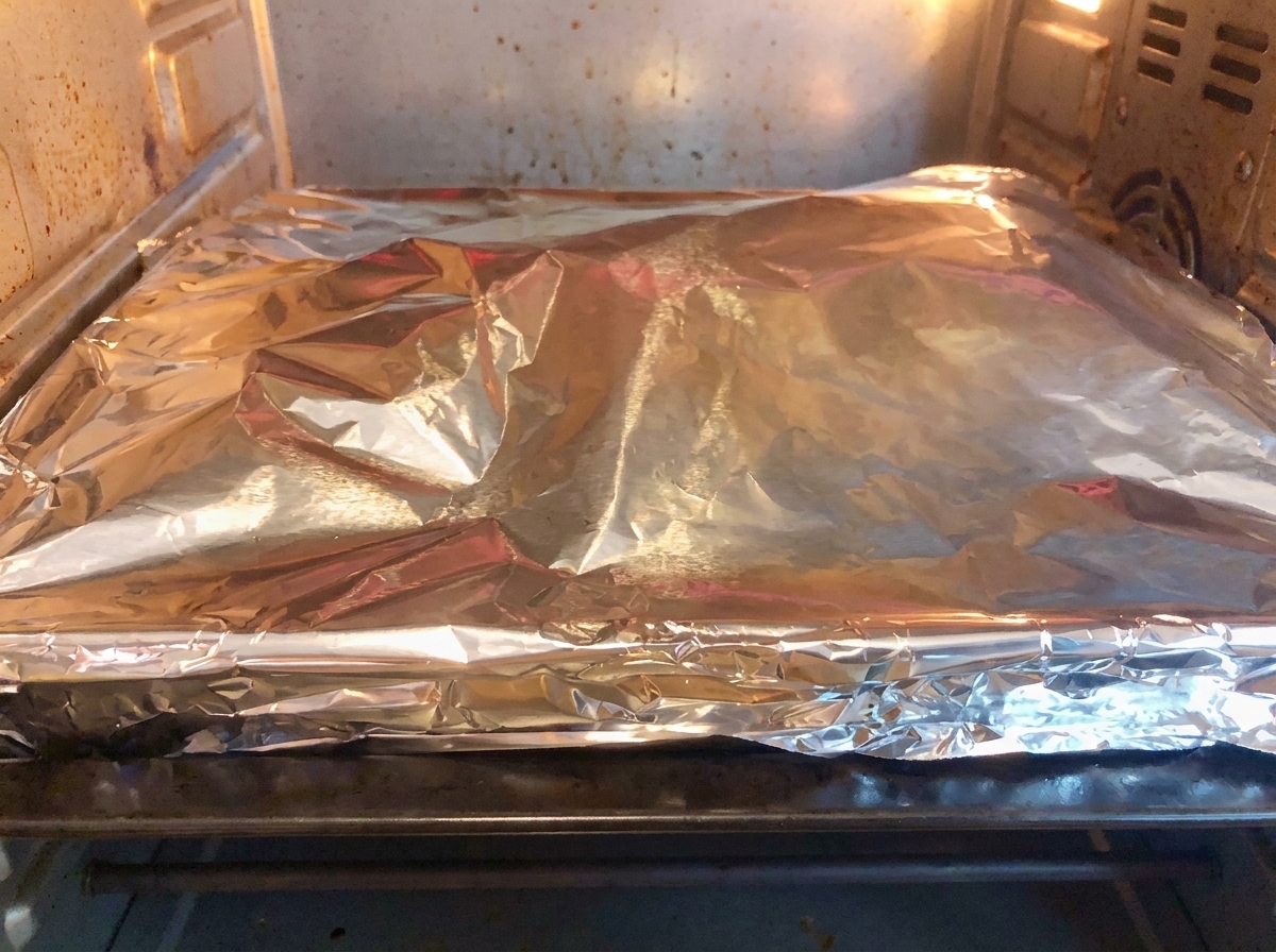 Un plat de cuisson recouvert de papier daluminium installé dans un four domestique chaud pour la cuisson.