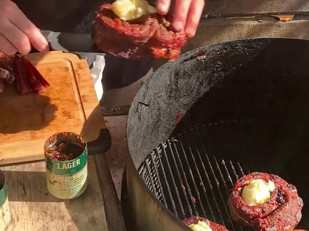 Installation dun panier de ribs farci sur un barbecue au charbon à côté dun autre panier et de tranches épaisses de bacon.
