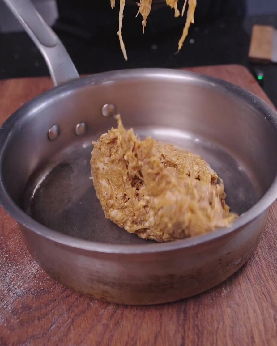Un dôme de porc effiloché savoureux en train de chauffer dans une petite casserole en inox.