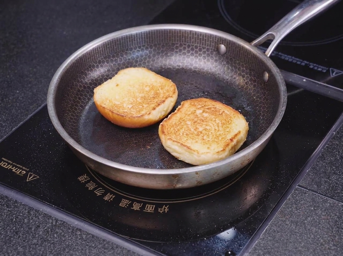 Deux moitiés dun pain brioché posées face contre terre dans une poêle alvéolée, toastant jusquà ce que les bords soient dorés.