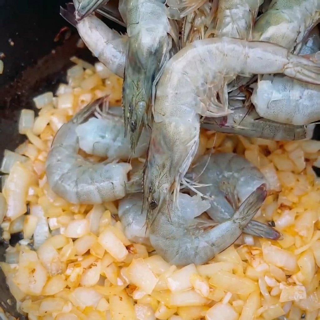 Crevettes grises entières déposées sur un lit doignons rissolés.