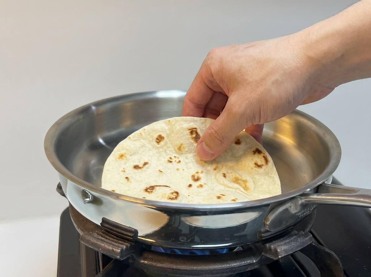 Une tortilla est posée sur une poêle chaude en acier inoxydable.