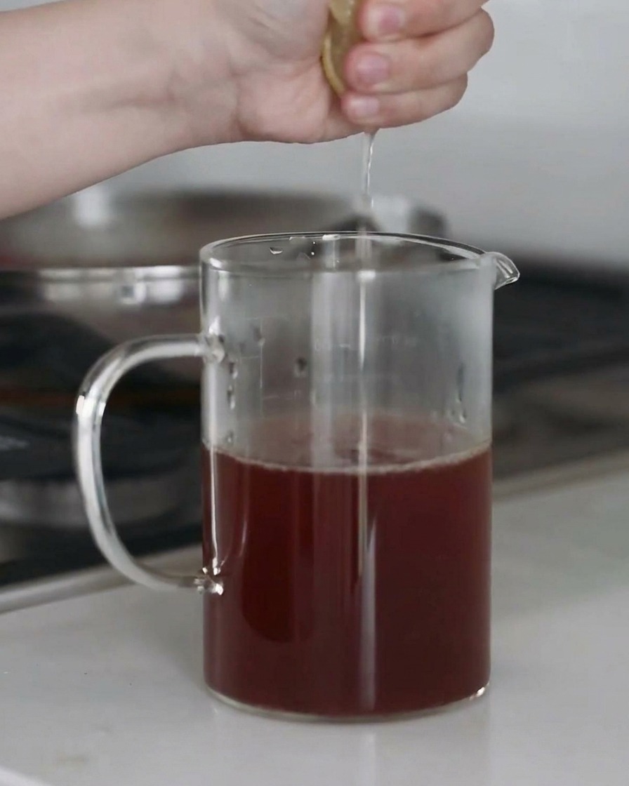 Jus de citron frais pressé dans un bol de bouillon assaisonné, avec des gouttelettes capturées en plein vol.