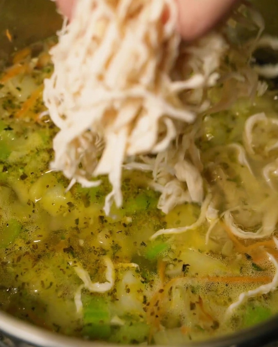 Poulet effiloché ajouté au bouillon frémissant.