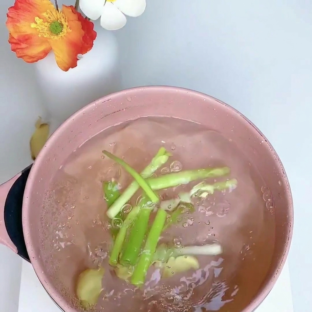 Cuisse de poulet mijotant dans une casserole deau avec de loignon nouveau, du gingembre et de lanis étoilé.