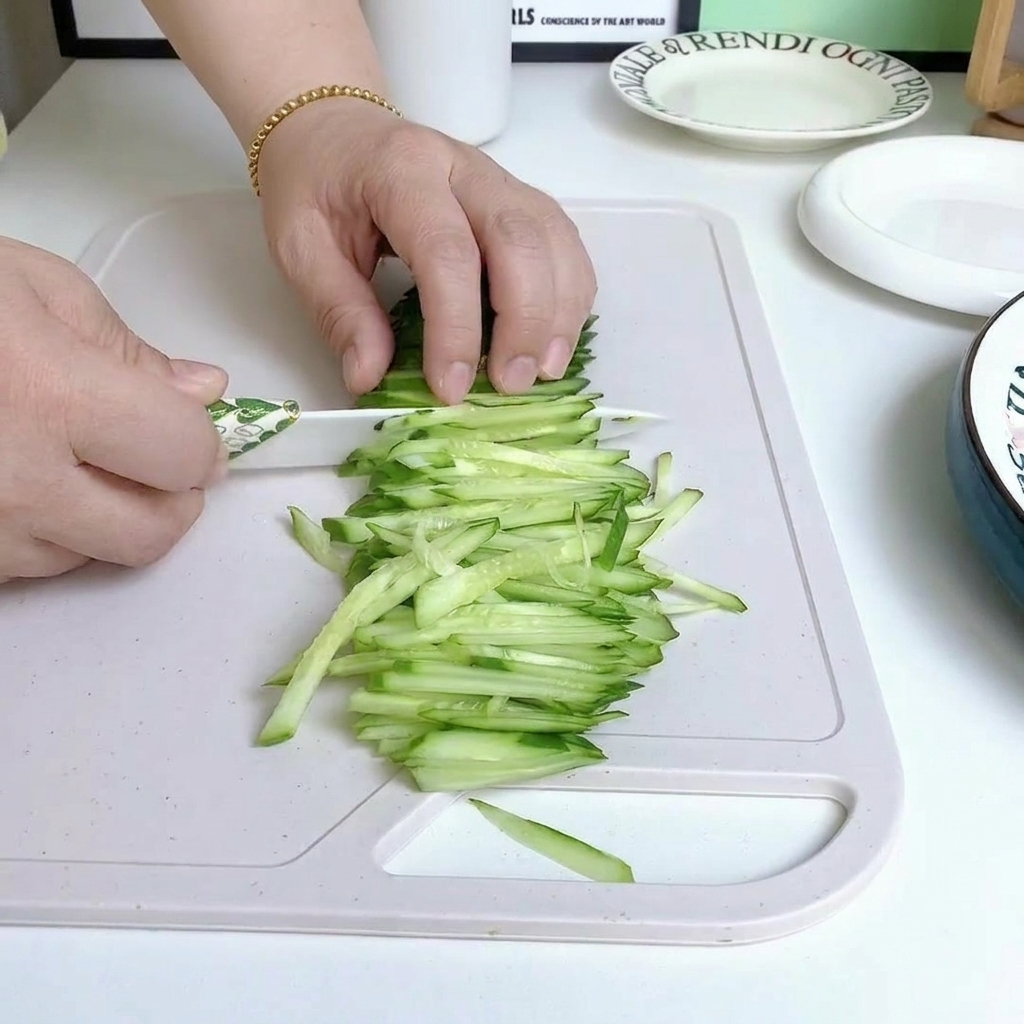 Concombre frais coupé en fines lamelles sur une planche à découper en bois.