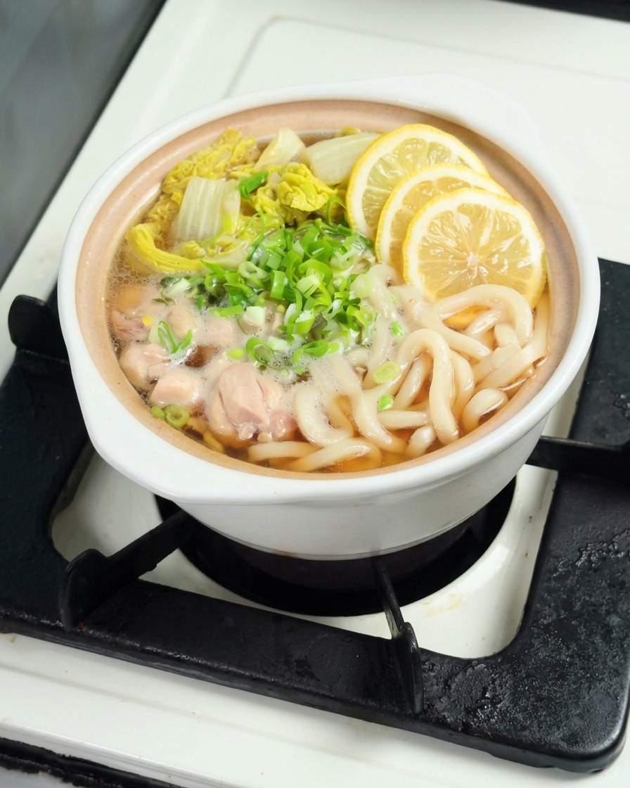 Tranches de citron jaune frais posées délicatement sur le dessus dun bol de nouilles udon fumant.