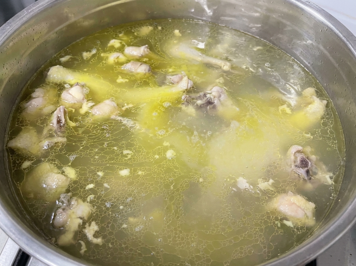 Ajout des assaisonnements dans le bouillon de poulet doré frémissant.