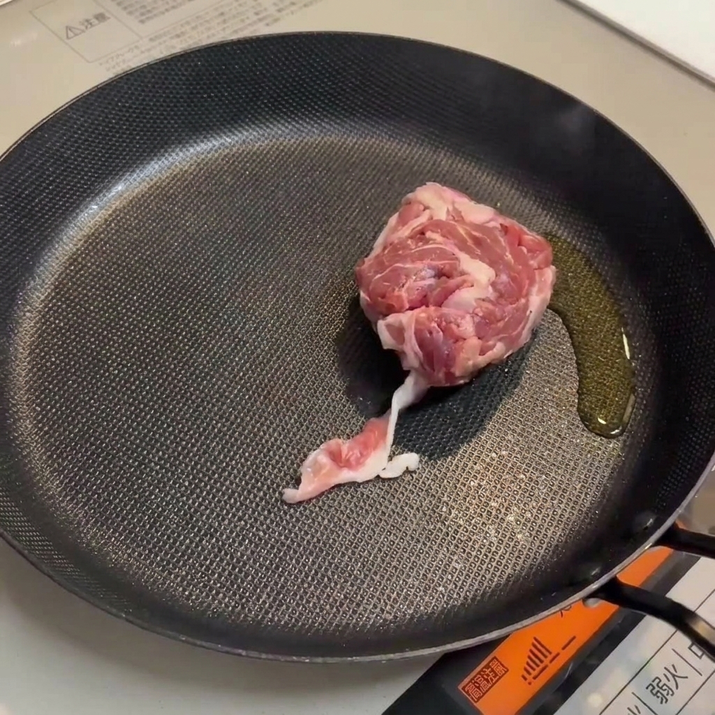 Porc et saucisses dorant dans une poêle, créant une base savoureuse.