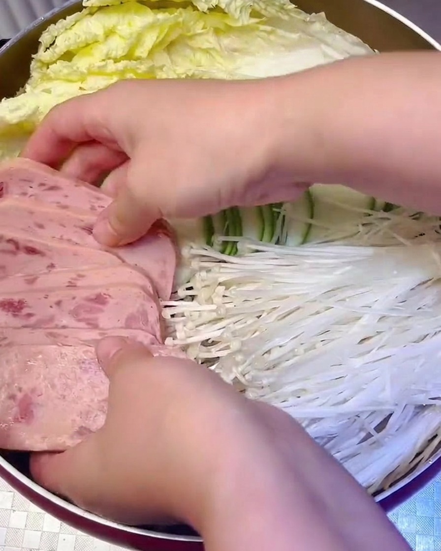 Tranches de viande en conserve et champignons enoki disposés systématiquement dans la marmite.