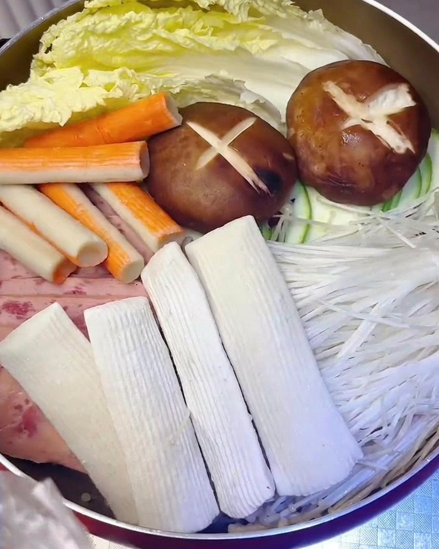 Gâteaux de poisson et bâtonnets de crabe ajoutés dans la marmite avec la viande et les légumes.