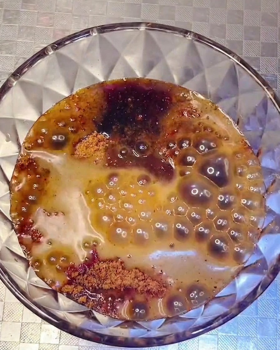 Sauce sombre et savoureuse versée depuis un bol dans une marmite garnie dingrédients.