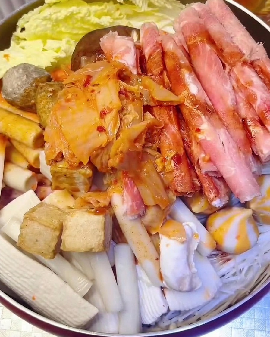 Tas de kimchi haché ajouté dans la marmite avec de leau versée par-dessus.
