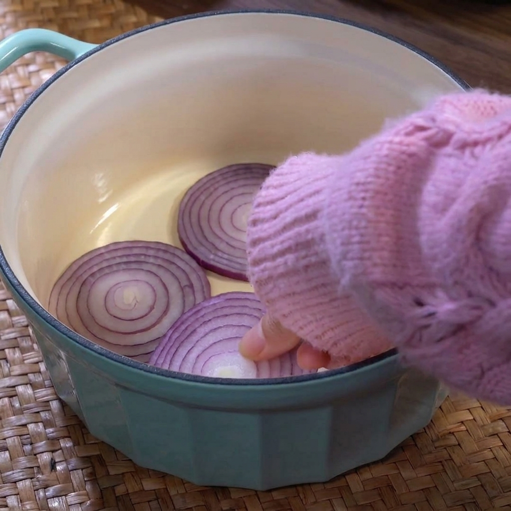 Marmite bleu clair avec une couche doignons, de chou et de racines de lotus au fond.