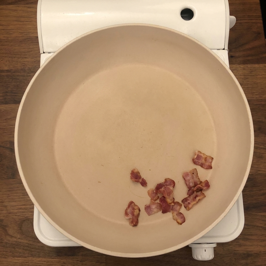 Des oignons et du céleri hachés ajoutés dans la poêle avec les morceaux de bacon croustillants.
