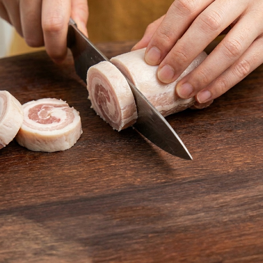 Tranches de lard coupées en petits morceaux sur une planche à découper.