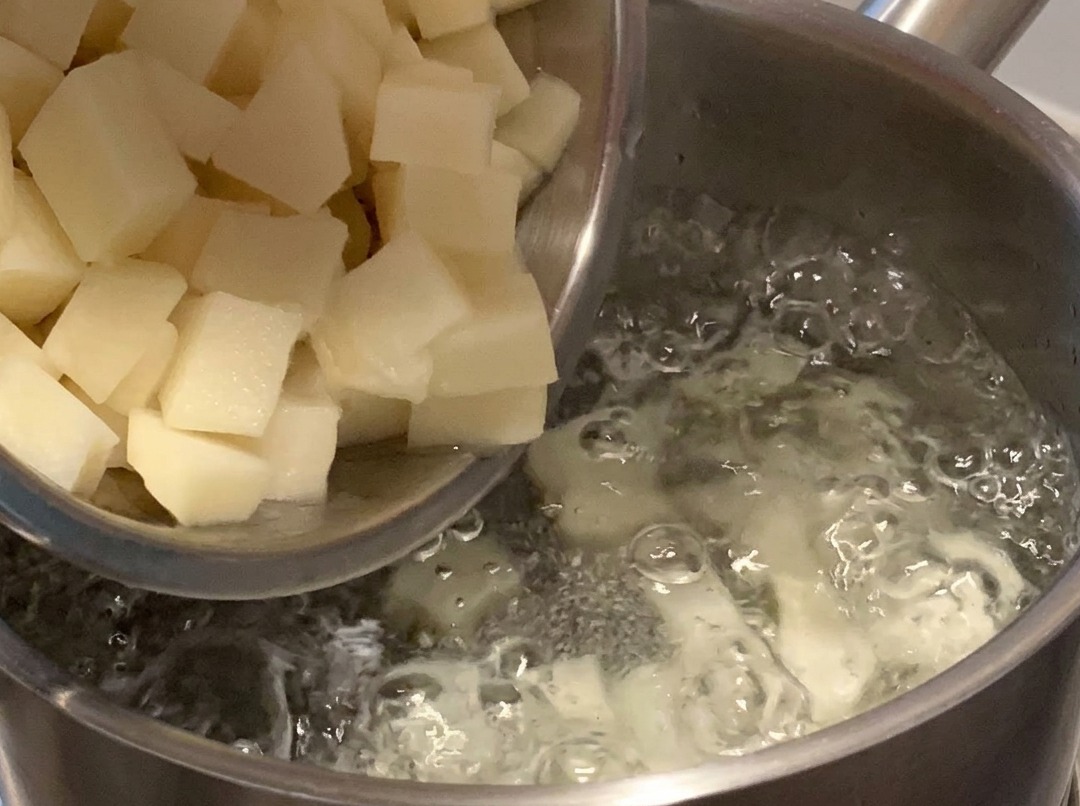 Dés de pommes de terre bouillant dans une casserole deau sur la cuisinière.