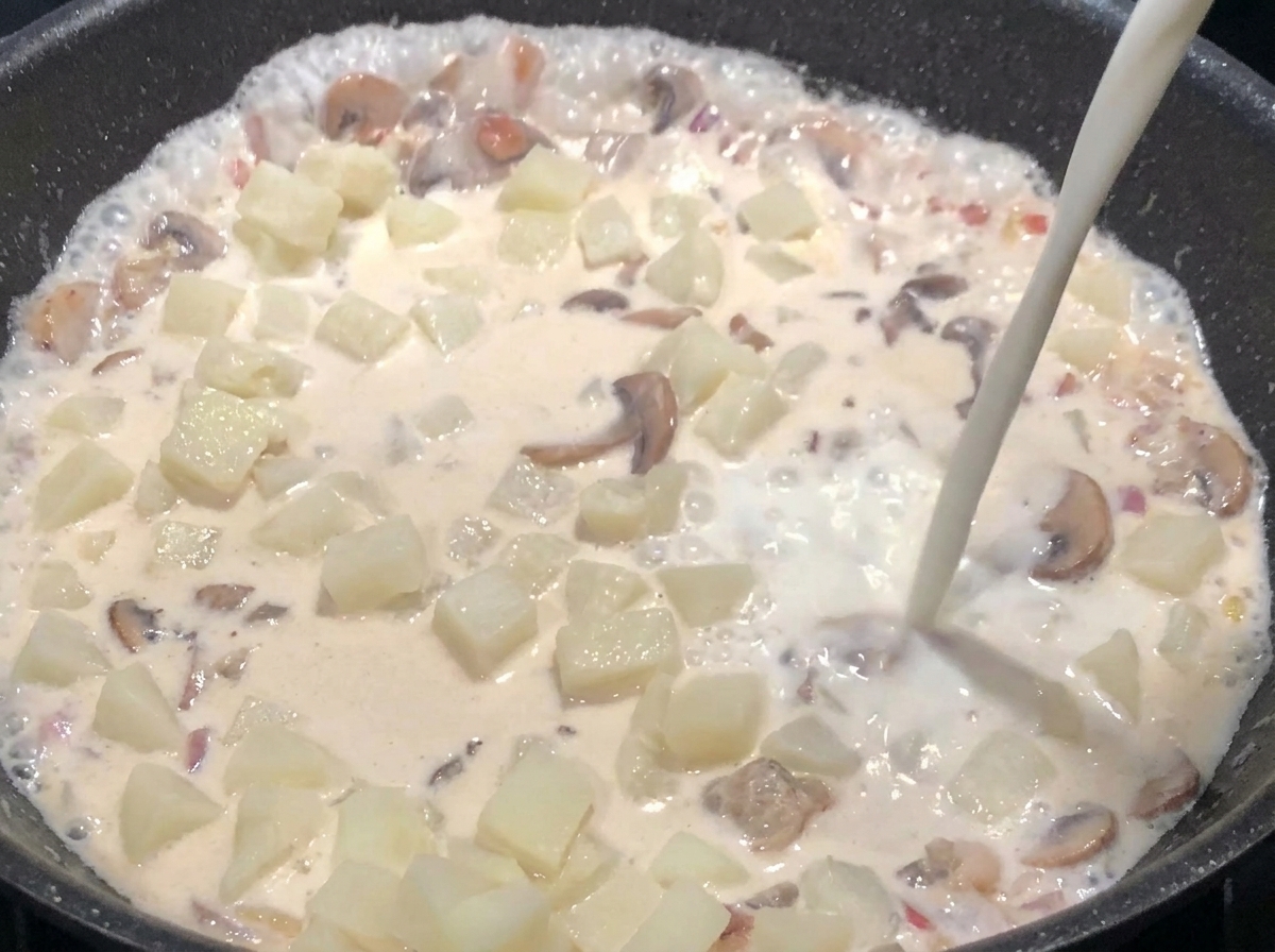 Lait versé dans la poêle jusquà immersion des ingrédients, tandis que la soupe épaissit.