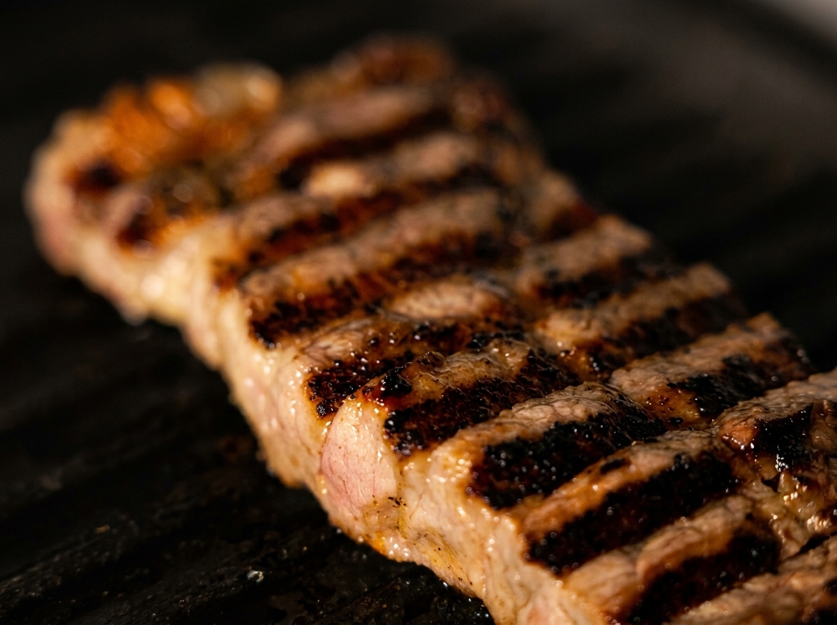 Gros plan sur un faux-filet épais avec des marques de gril bien marquées.