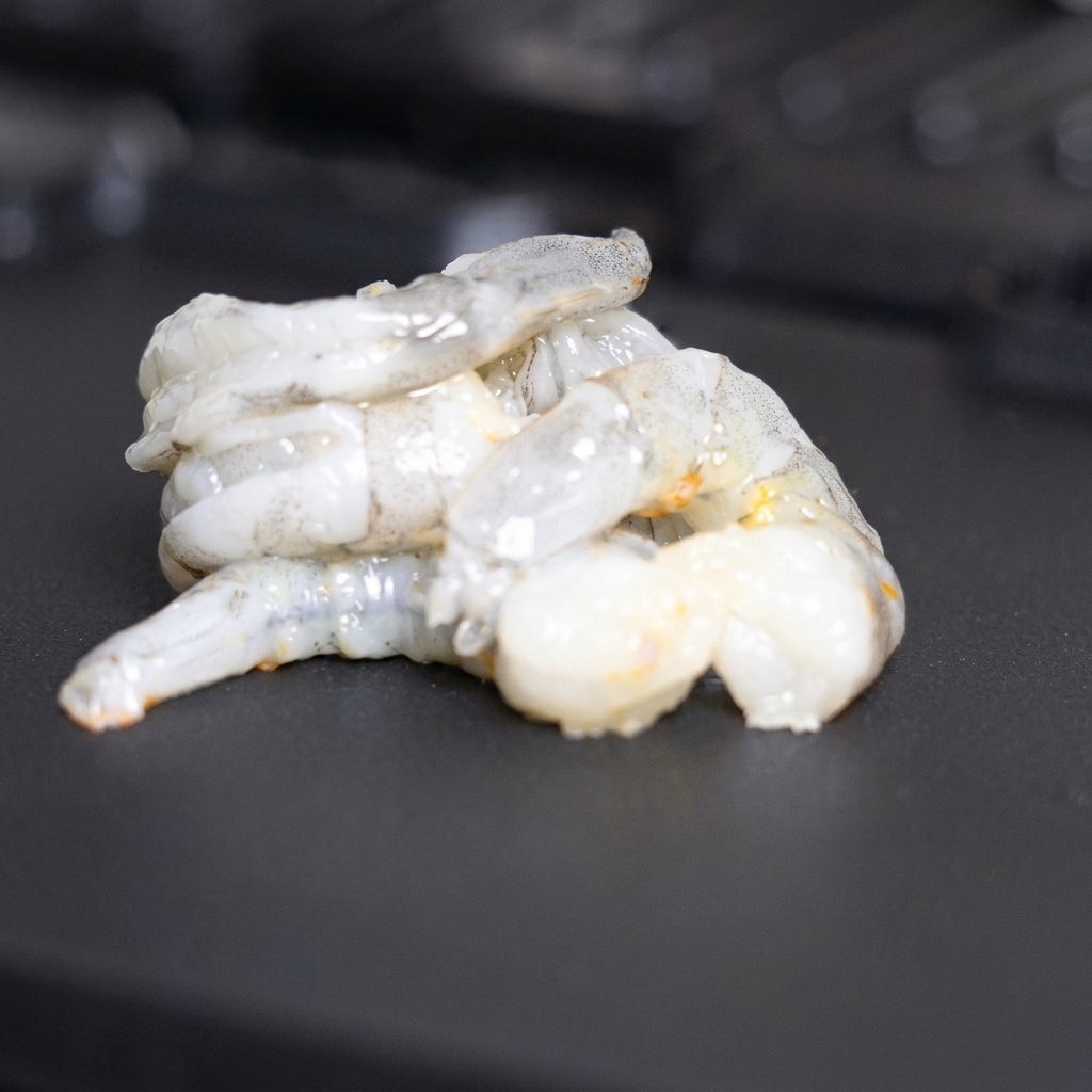 Crevettes fraîches disposées et retournées sur une partie propre du gril.