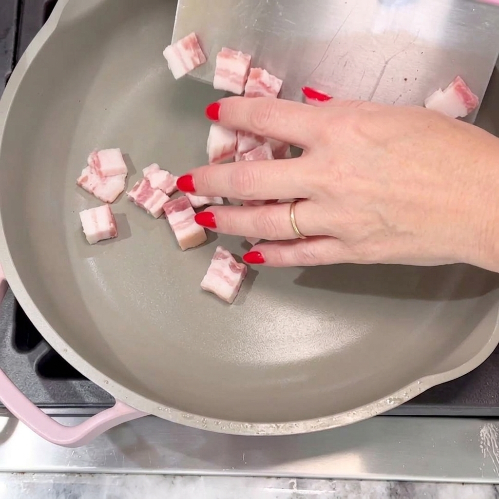 Dés de bacon déposés dans une poêle pour frire jusquà devenir dorés.