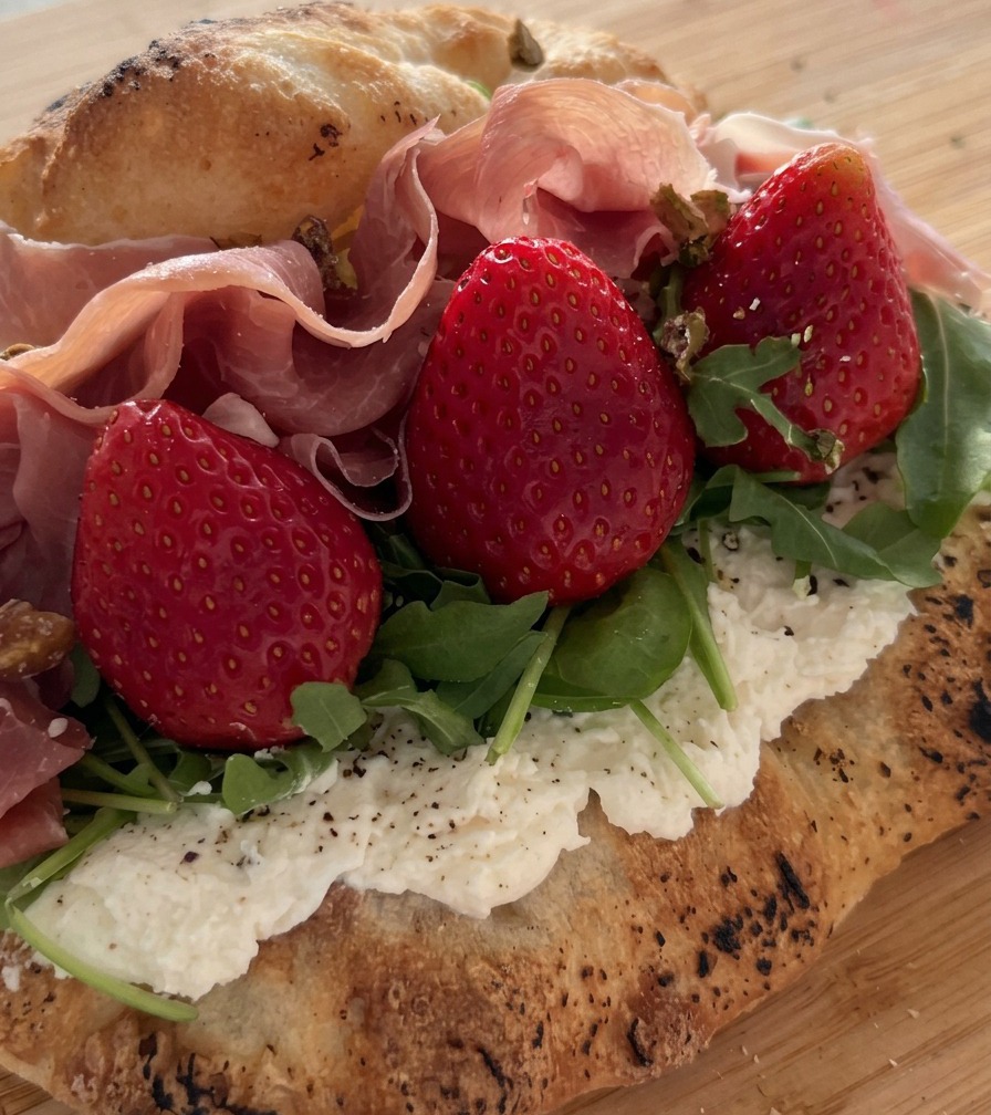 Pistaches concassées saupoudrées sur un sandwich garni de prosciutto, fraises et roquette.