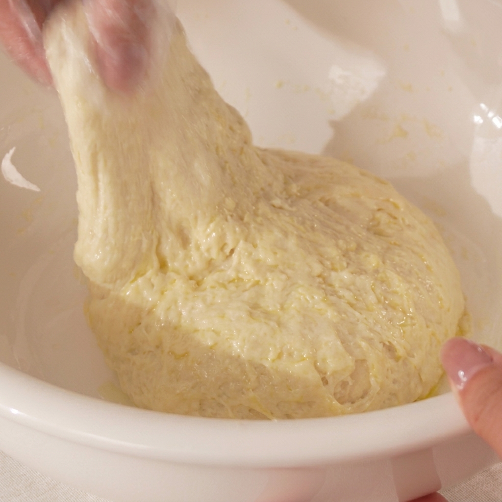 Gros plan sur les mains étirant et repliant la pâte.