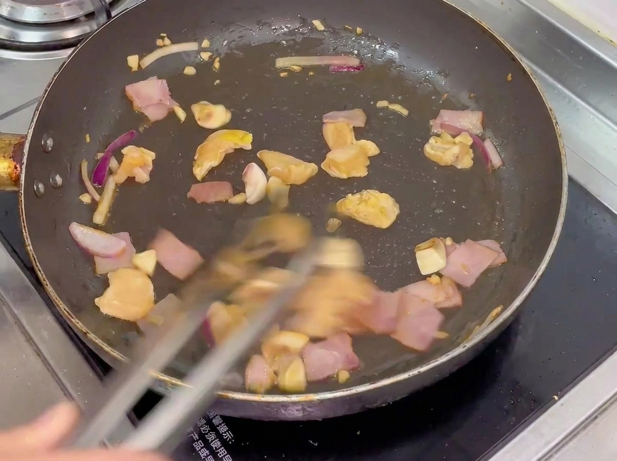 Un mélange de poulet, bacon, champignons et oignons en train dêtre sauté dans une poêle chaude.