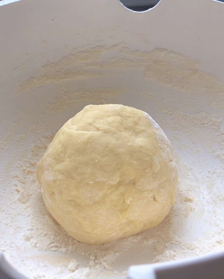 Une boule de pâte crue, lisse et ronde, reposant au centre dun bol à mélanger blanc.