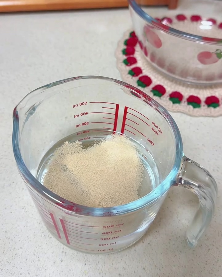 Granulés de levure sèche à la surface de leau dans un verre doseur.