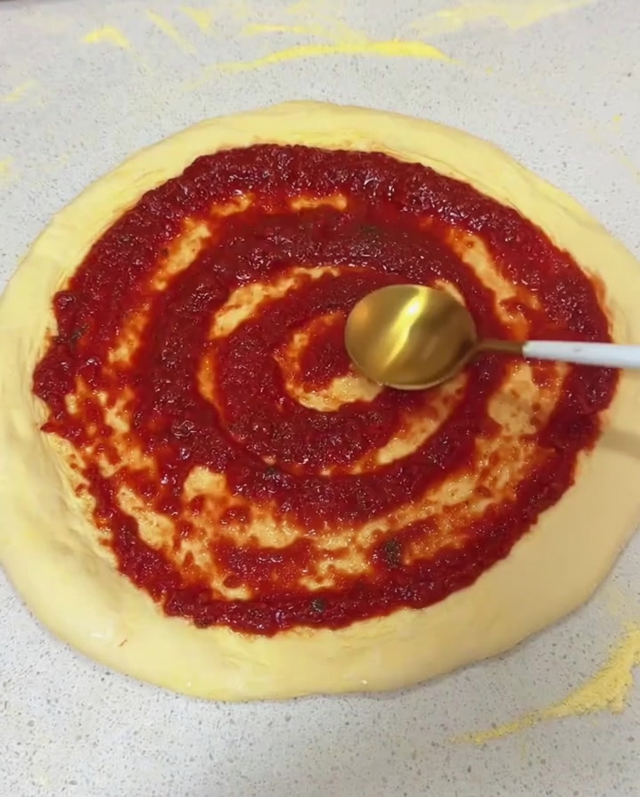 Étaler la sauce tomate en mouvement circulaire sur la pâte.