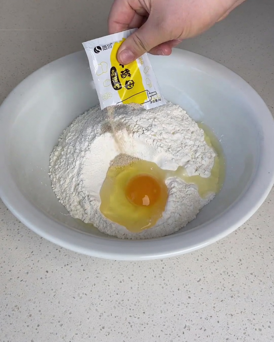 Levure, sucre et sel saupoudrés sur la farine.