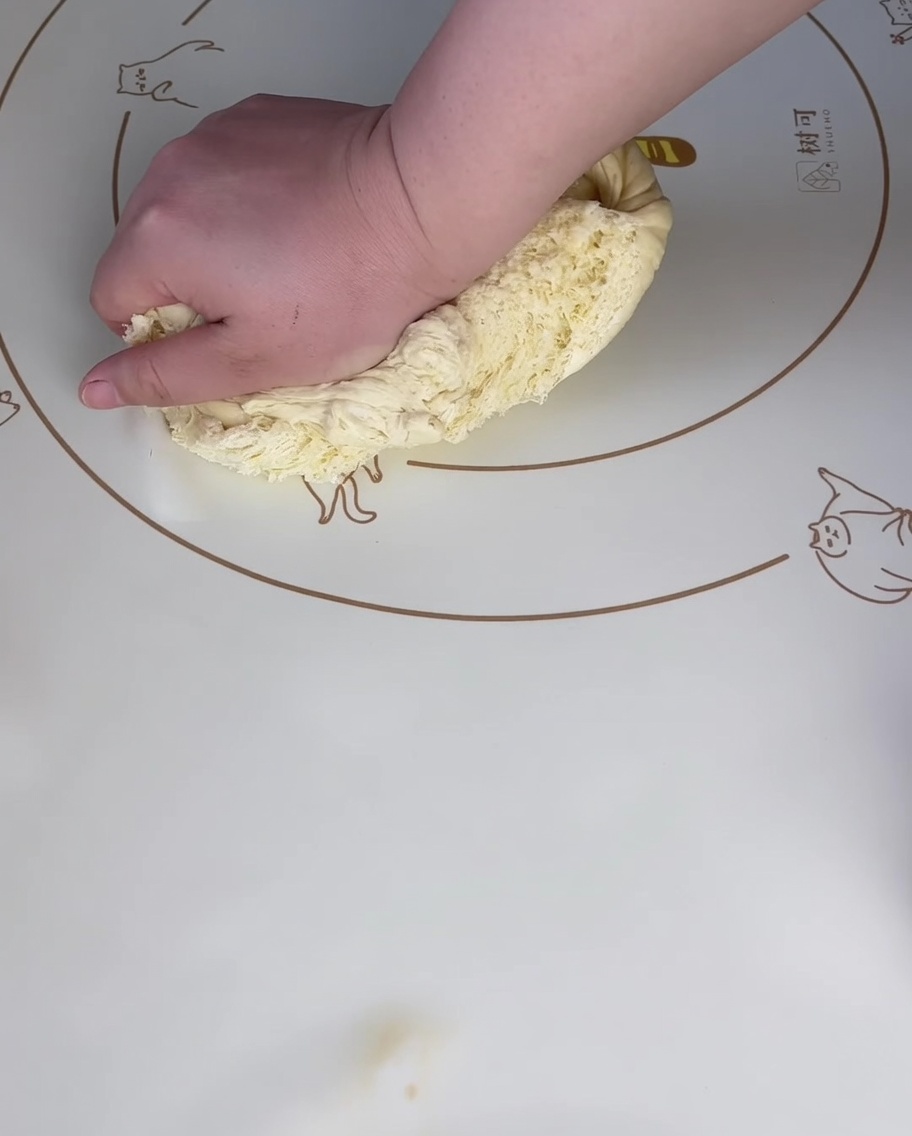 Main pressant la pâte sur un tapis en silicone.