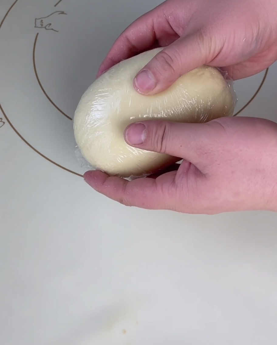 Boule de pâte reposant sous un film plastique.