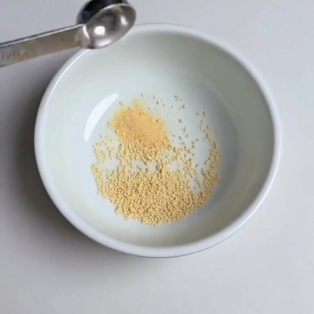 Cuillères à mesurer ajoutant de lail en poudre, du sucre et de la pâte de gochujang dans le bol.