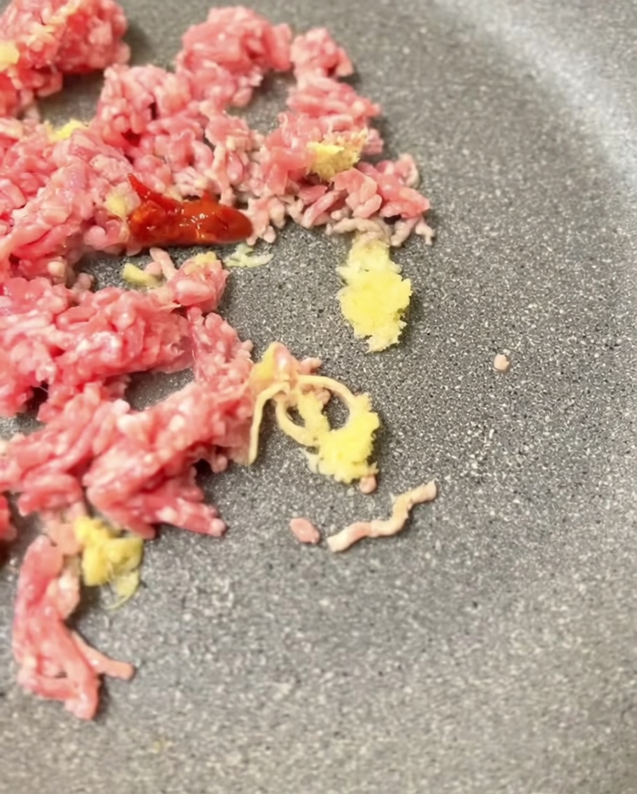 Pâte miso mélangée au porc doré dans une poêle.