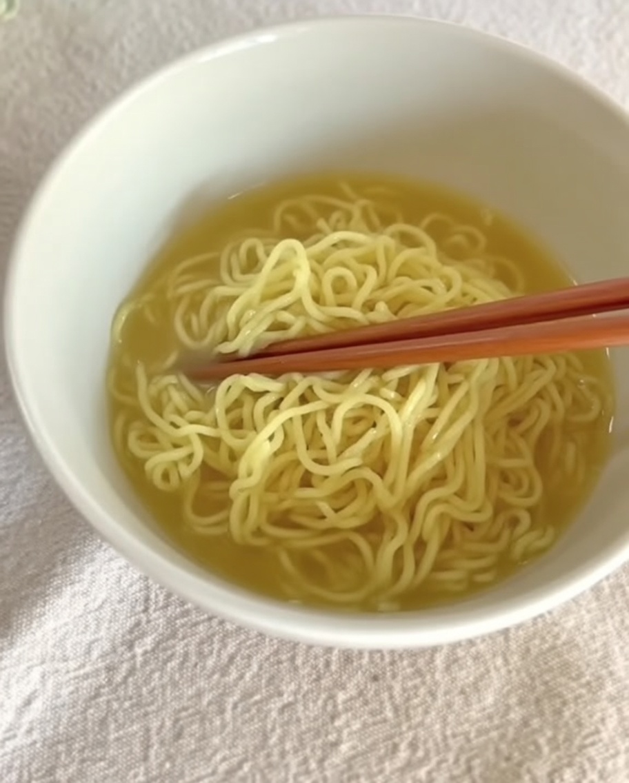 Bouillon Tantanmen crémeux versé sur les nouilles préparées dans un grand bol.