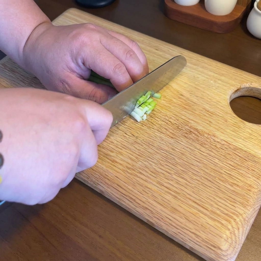 Ail, gingembre et oignons verts finement hachés sur une planche à découper en bois.