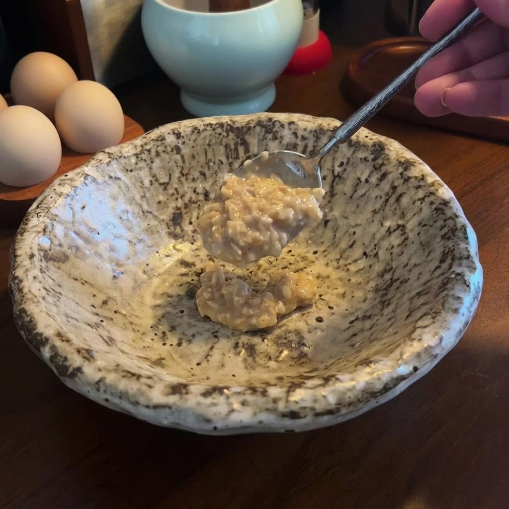 Une cuillerée de pâte miso et sésame épaisse ajoutée dans un bol de service en céramique mouchetée.