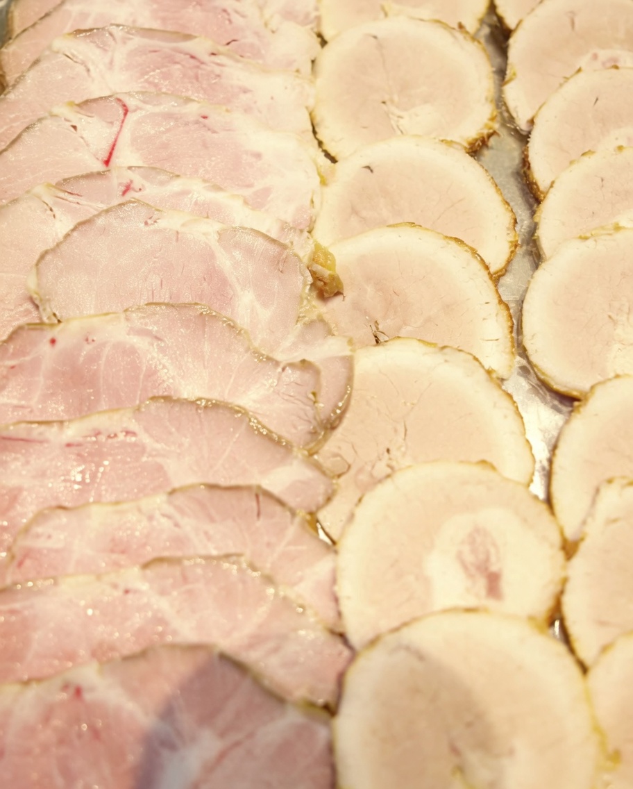 Des tranches fines de porc chashu disposées sur un plateau, prêtes à être servies.
