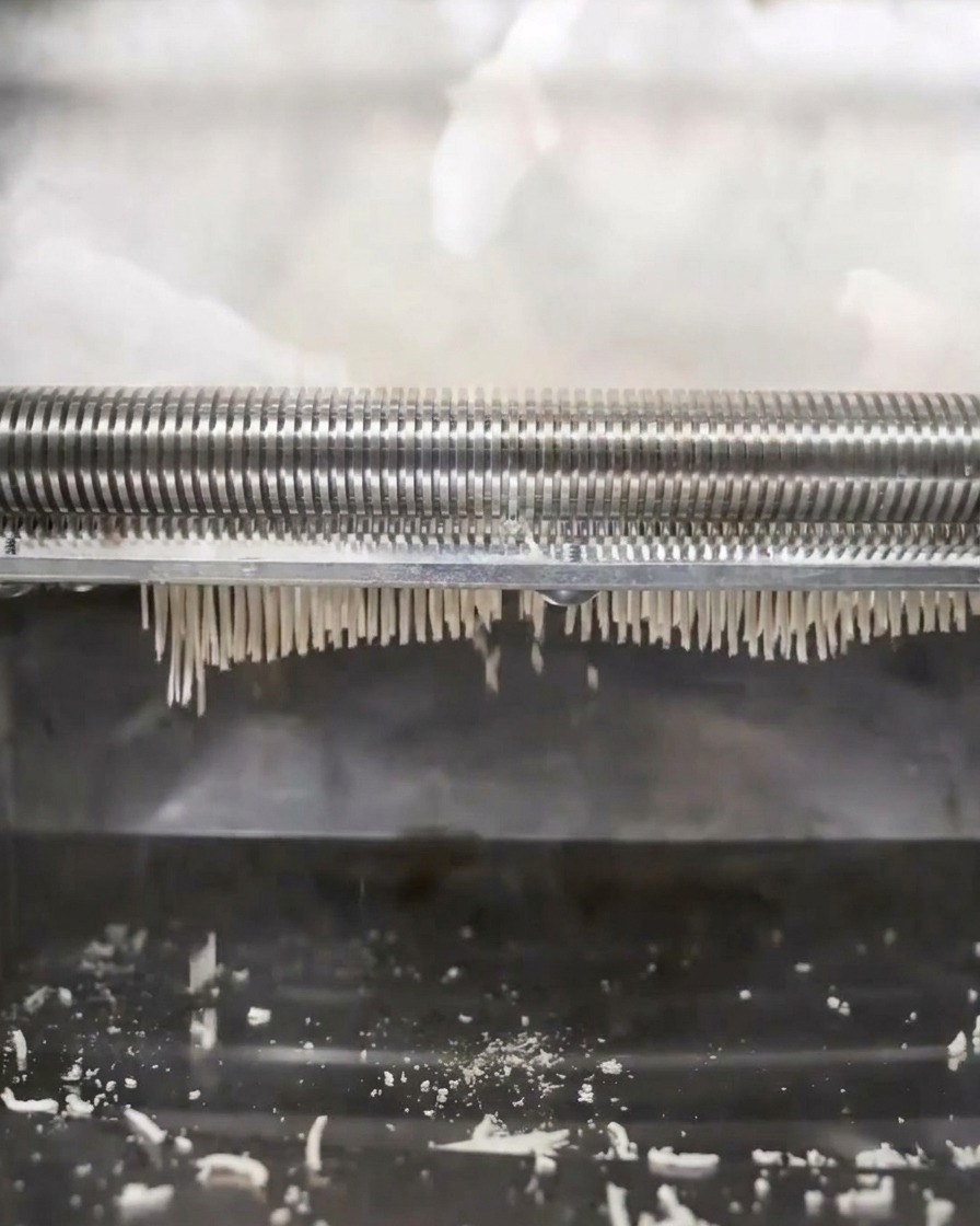 Machine à nouilles transformant la pâte en brins fins.