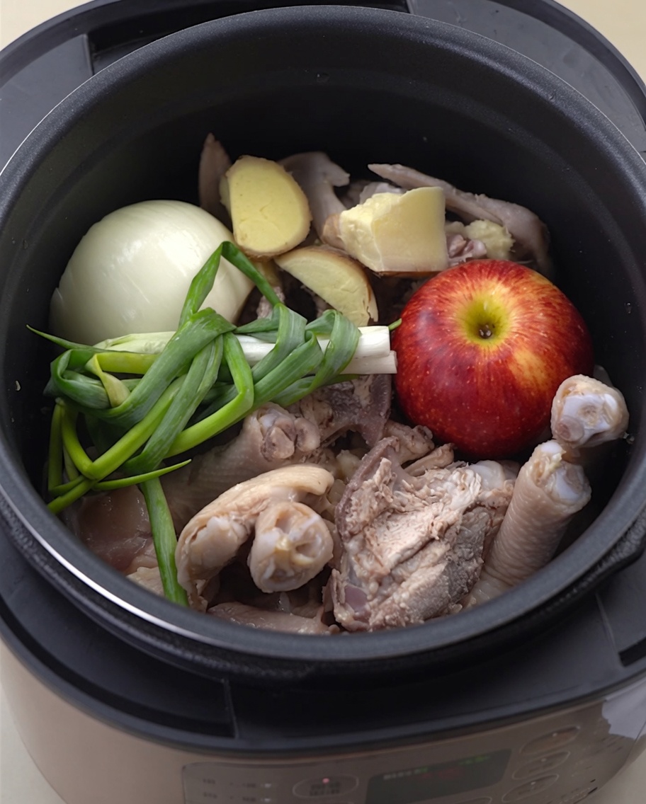 Eau versée dans lautocuiseur sur le poulet et les aromates.