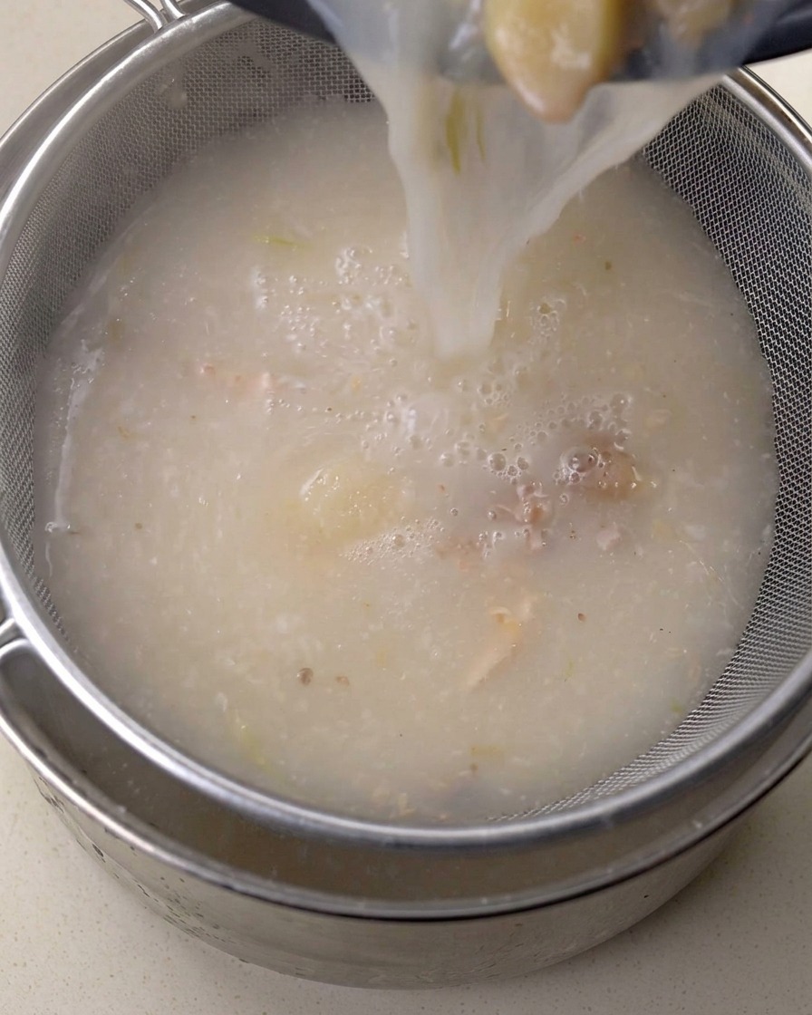 Bouillon riche versé à travers une fine passoire en métal.