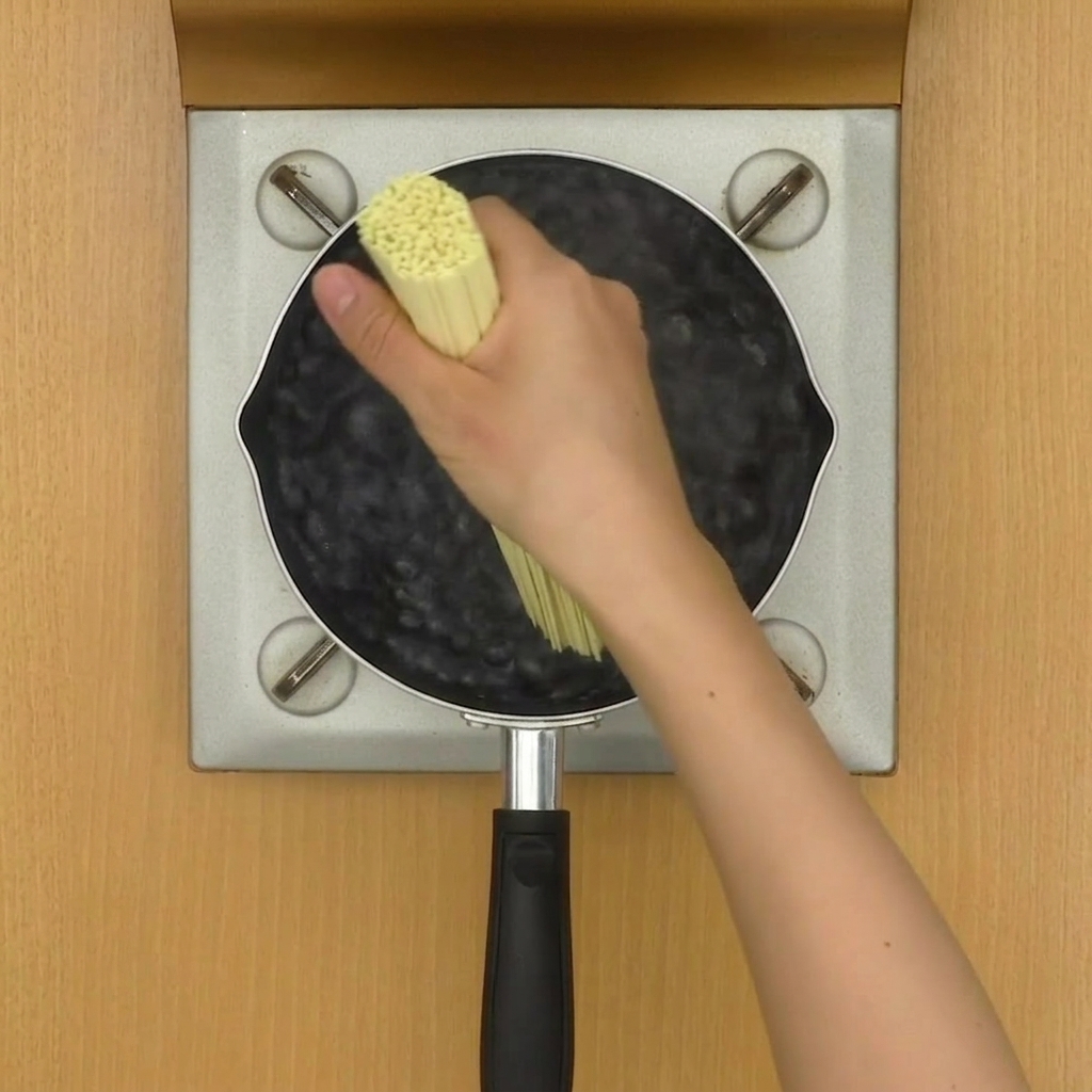 Nouilles ramen bouillant dans une marmite deau, remuées avec des baguettes.
